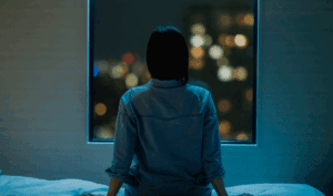 ベットの上で悩む女性